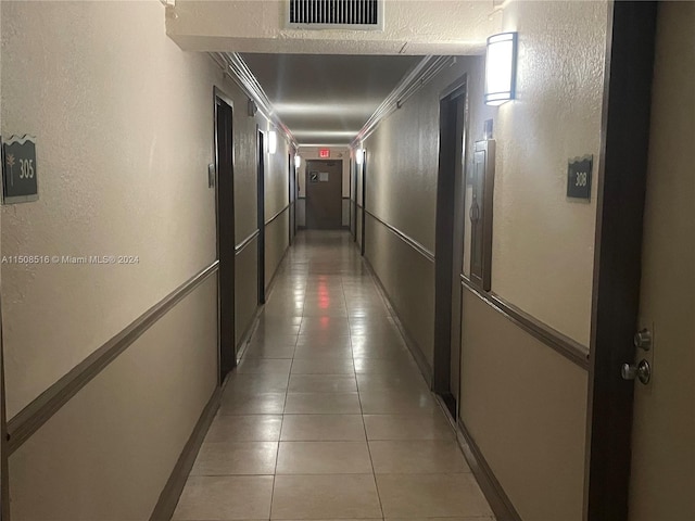 corridor with dark tile floors and ornamental molding