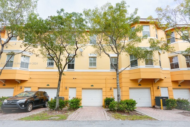 view of front of home featuring a balcony, central AC, and a garage