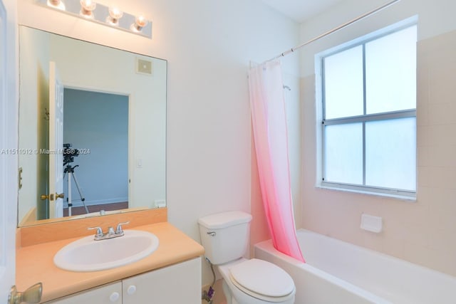 full bathroom featuring a wealth of natural light, vanity, shower / tub combo, and toilet