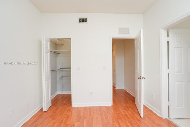 unfurnished bedroom featuring hardwood / wood-style floors, a spacious closet, and a closet