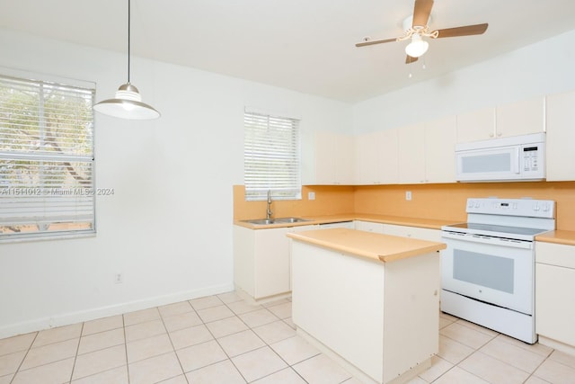 kitchen featuring sink, white appliances, a healthy amount of sunlight, and a center island