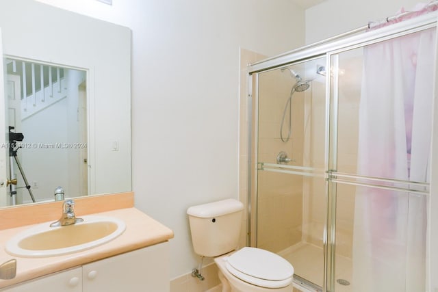 bathroom with toilet, an enclosed shower, and vanity