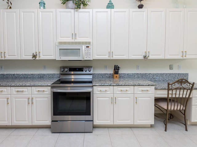 kitchen featuring white cabinets, light tile patterned floors, and electric stove