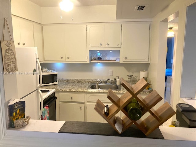 kitchen featuring sink, white appliances, and white cabinets