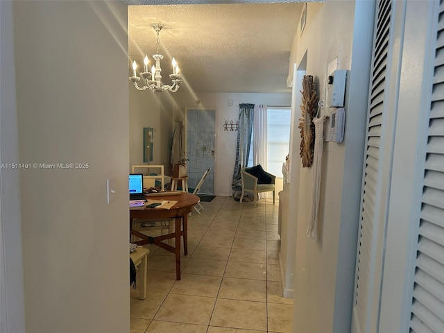 hallway featuring a textured ceiling, light tile patterned flooring, and a chandelier