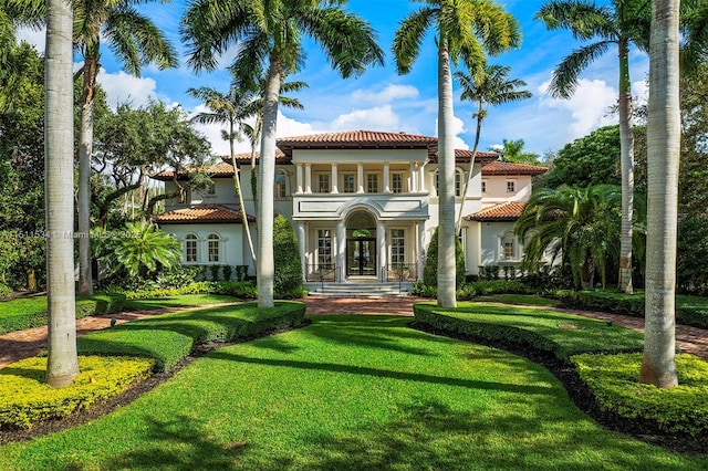 rear view of house featuring a tile roof, french doors, a yard, and stucco siding