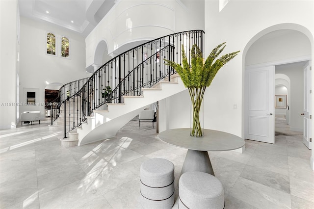 entryway with a towering ceiling, arched walkways, stairs, marble finish floors, and recessed lighting