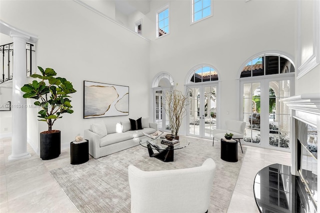 living room featuring a towering ceiling, ornate columns, french doors, and a premium fireplace