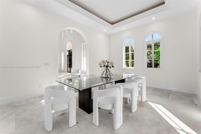 dining area featuring a tray ceiling and light tile patterned flooring