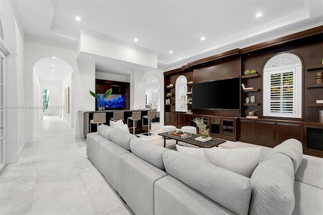 living area with arched walkways, a tray ceiling, recessed lighting, and baseboards