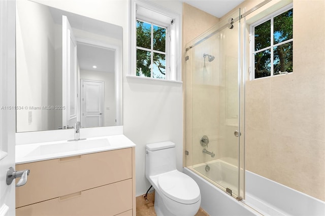 bathroom featuring toilet, combined bath / shower with glass door, and vanity
