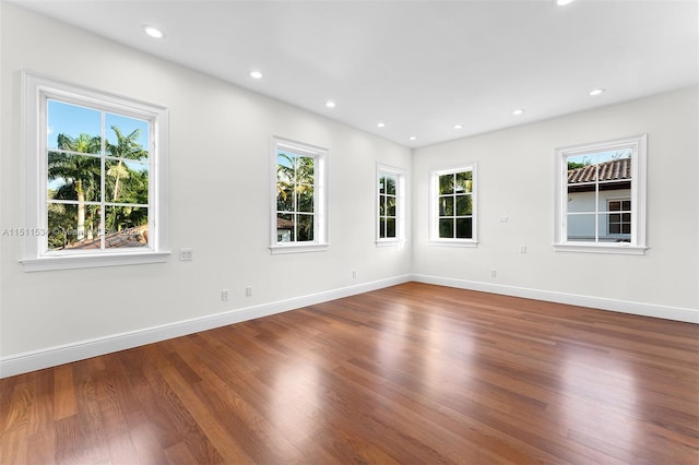 empty room featuring plenty of natural light, wood finished floors, baseboards, and recessed lighting