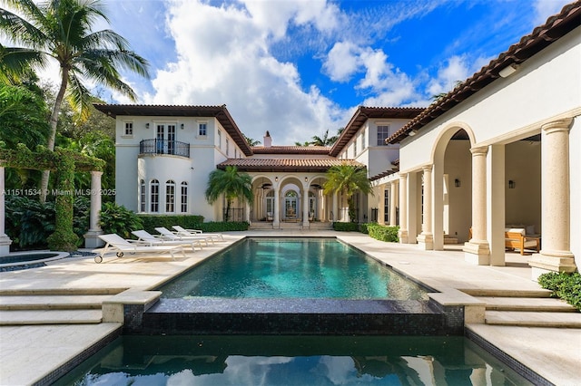 rear view of property with a tile roof, stucco siding, a patio, a balcony, and french doors