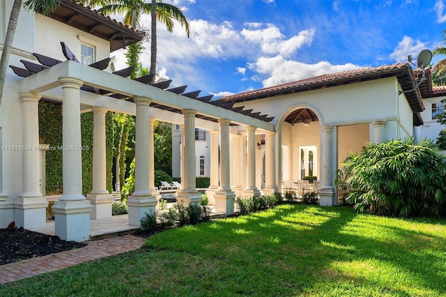 rear view of house with a tiled roof, a yard, a pergola, and stucco siding
