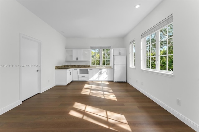 kitchen with white fridge, white cabinetry, and dark hardwood / wood-style floors