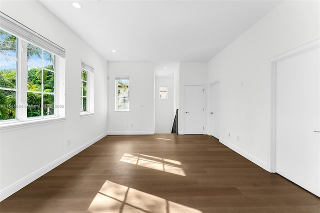 empty room with dark hardwood / wood-style floors and a healthy amount of sunlight