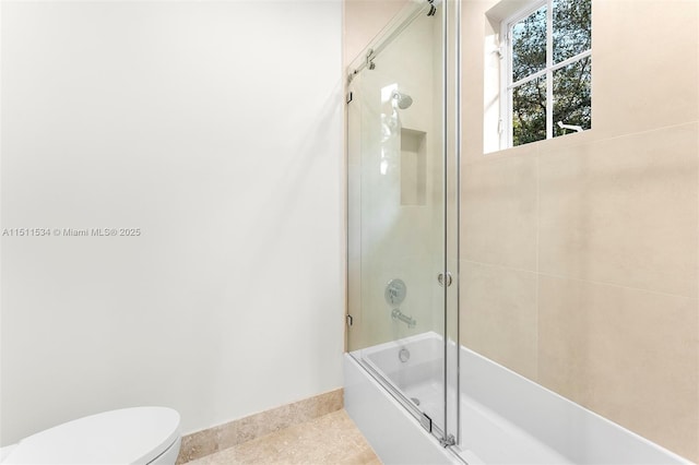 full bath featuring baseboards, combined bath / shower with glass door, toilet, and tile patterned flooring