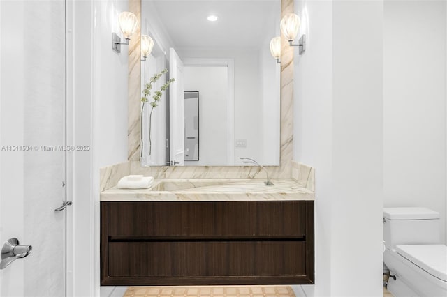 bathroom with toilet, vanity, and recessed lighting