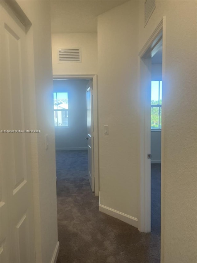 hallway with dark colored carpet