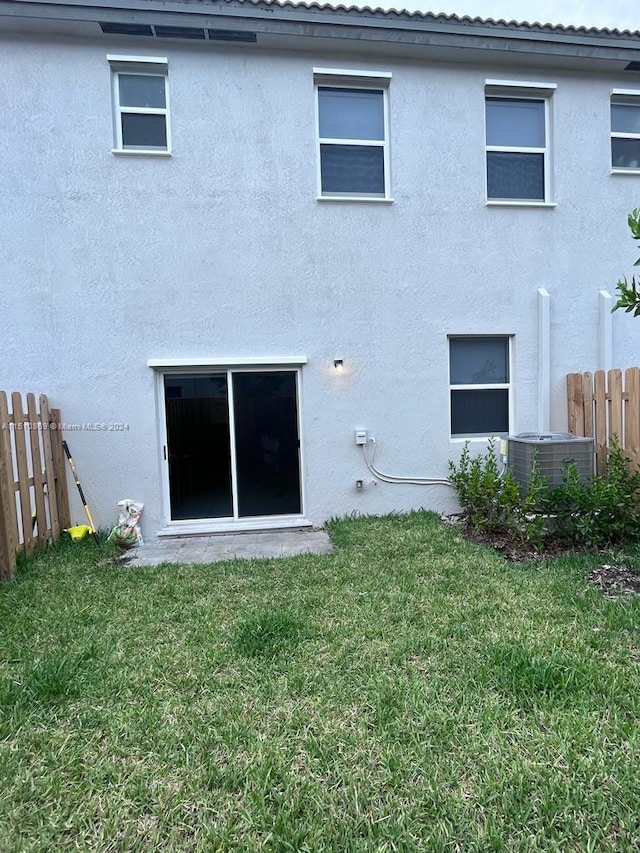 back of property featuring a yard and central AC