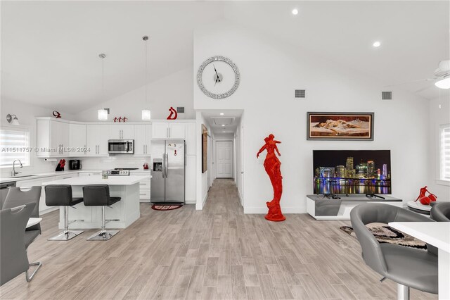 living room with sink, high vaulted ceiling, light hardwood / wood-style flooring, and ceiling fan