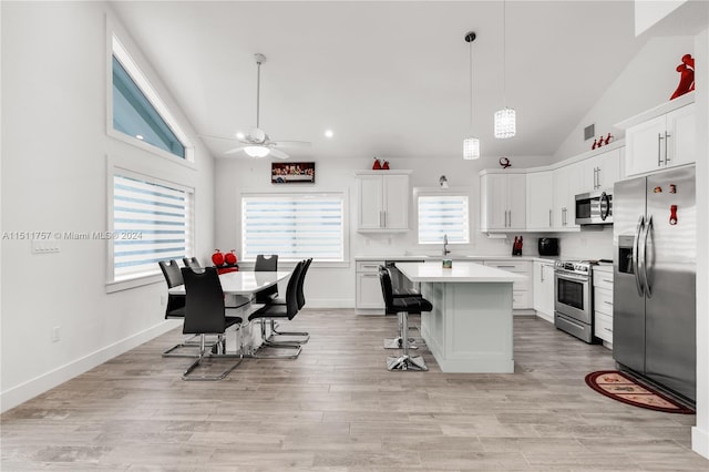 kitchen with ceiling fan, a center island, stainless steel appliances, and white cabinets