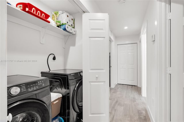 laundry room with light wood-type flooring and washing machine and dryer