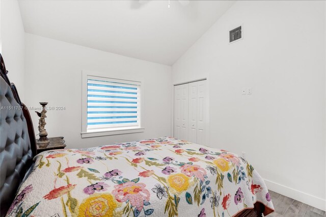 bedroom featuring ceiling fan, a closet, lofted ceiling, and hardwood / wood-style floors