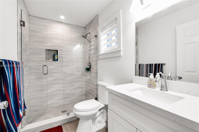 bathroom featuring toilet, a shower stall, and vanity