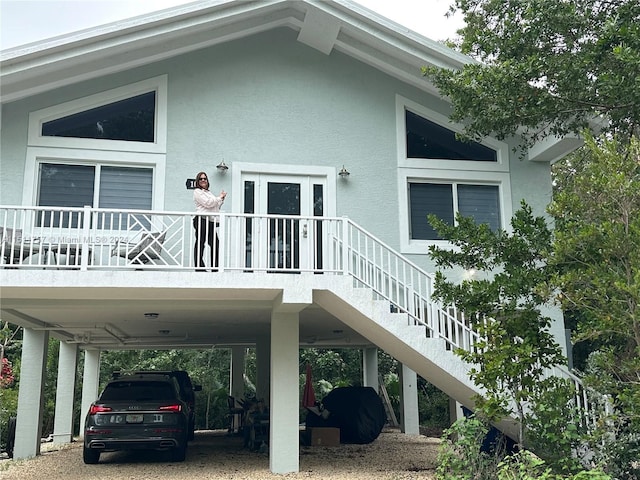 view of side of home with stairs, a carport, and stucco siding