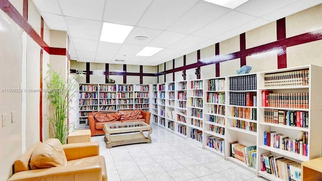 sitting room featuring a drop ceiling and light tile floors