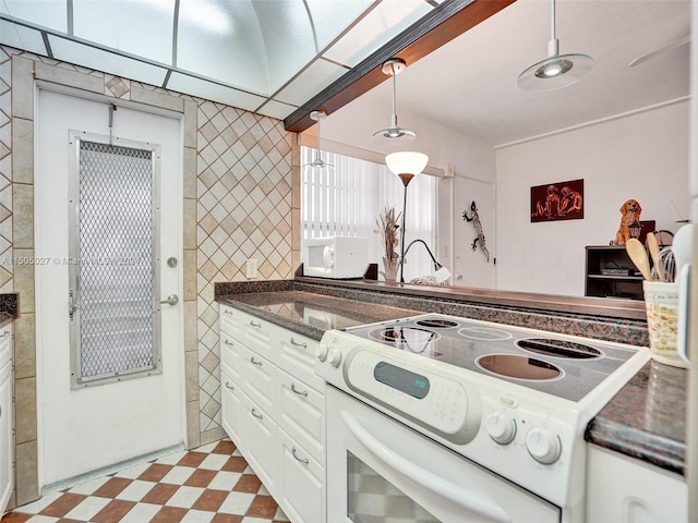 kitchen featuring white range oven, white cabinetry, light tile flooring, and decorative light fixtures