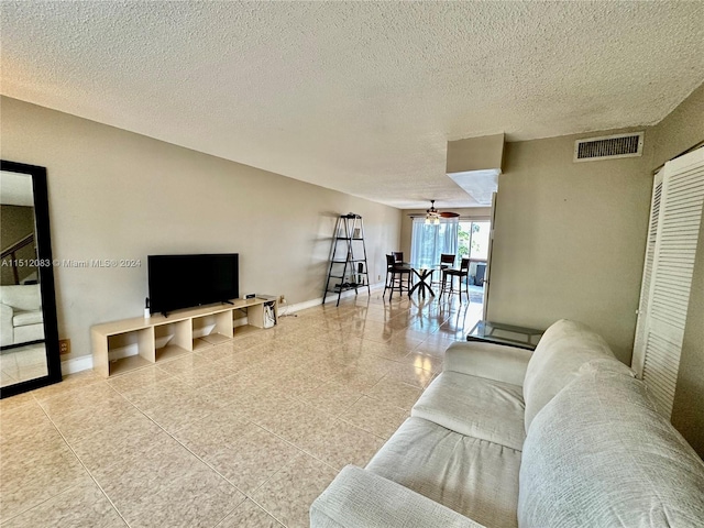 tiled living room featuring a textured ceiling and ceiling fan