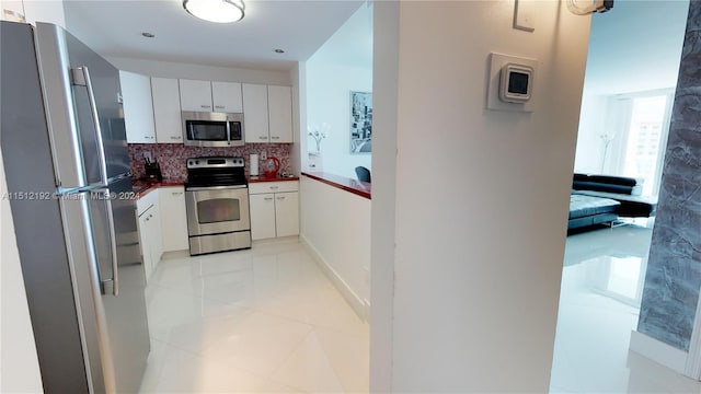 kitchen featuring backsplash, light tile floors, appliances with stainless steel finishes, and white cabinetry