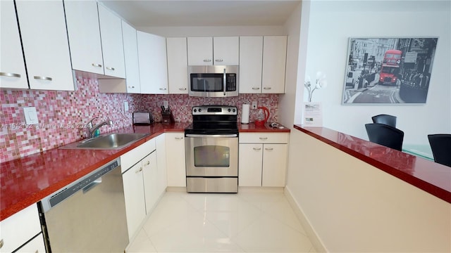 kitchen featuring backsplash, appliances with stainless steel finishes, sink, light tile floors, and white cabinets