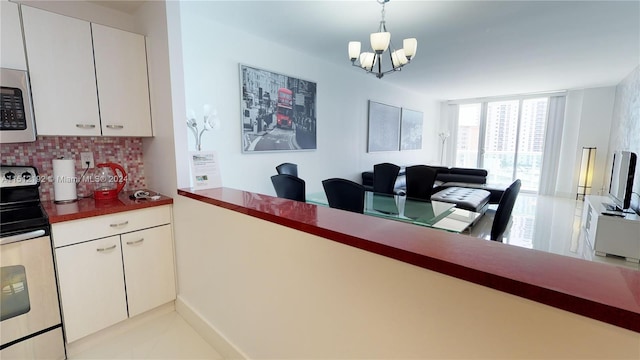 kitchen featuring decorative light fixtures, white cabinetry, backsplash, stainless steel appliances, and a chandelier