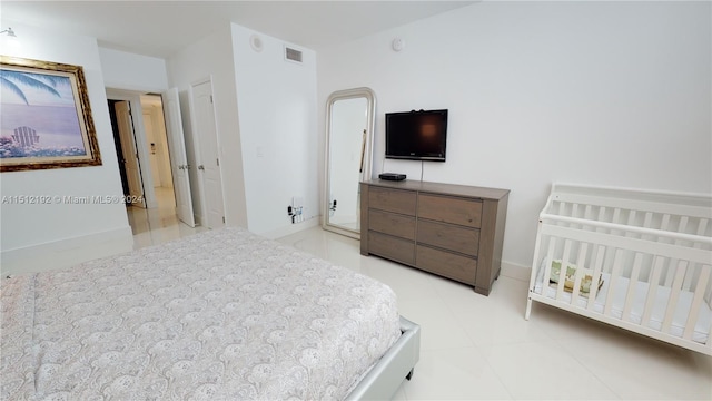 bedroom featuring a nursery area and light tile floors