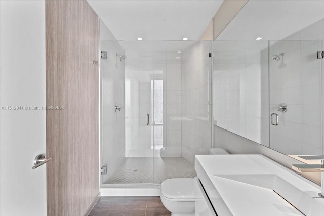 bathroom featuring toilet, a shower with door, and large vanity