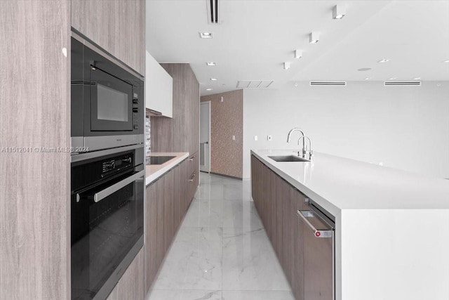 kitchen with a center island with sink, light tile floors, black appliances, and sink