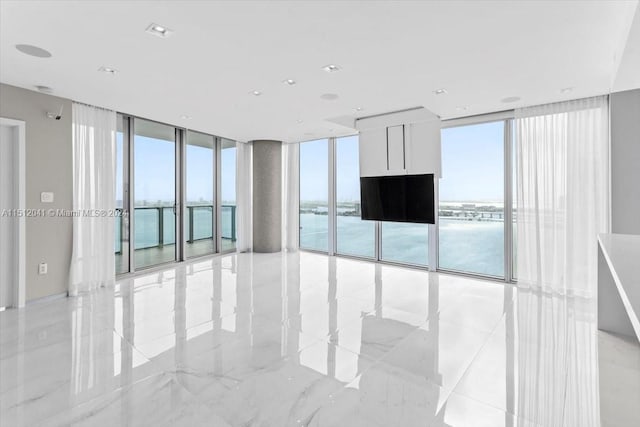 tiled spare room with a water view and floor to ceiling windows