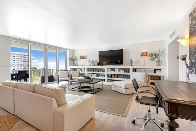 living room featuring light wood-type flooring and floor to ceiling windows