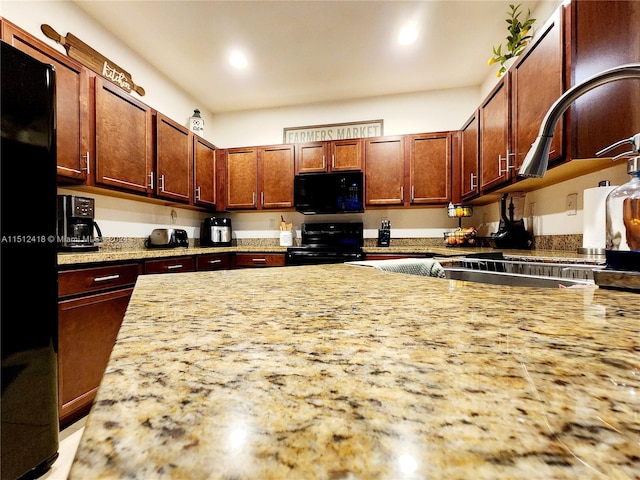 kitchen with light stone countertops and black appliances