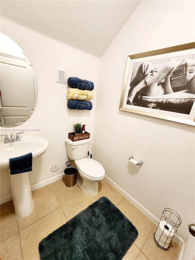 bathroom featuring sink, toilet, lofted ceiling, and tile patterned floors