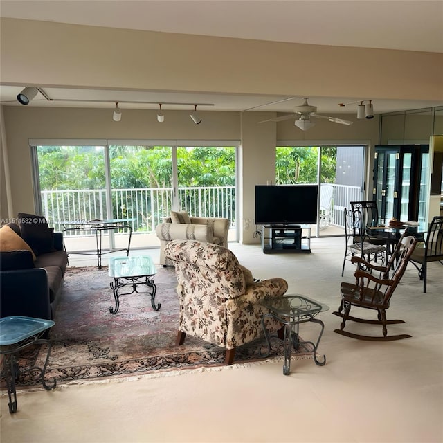 carpeted living room with rail lighting and ceiling fan