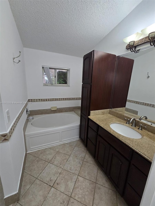 bathroom featuring tile patterned floors, a bathing tub, vanity, and a textured ceiling