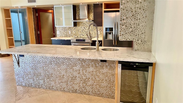 kitchen featuring light tile patterned flooring, appliances with stainless steel finishes, tasteful backsplash, wine cooler, and wall chimney exhaust hood