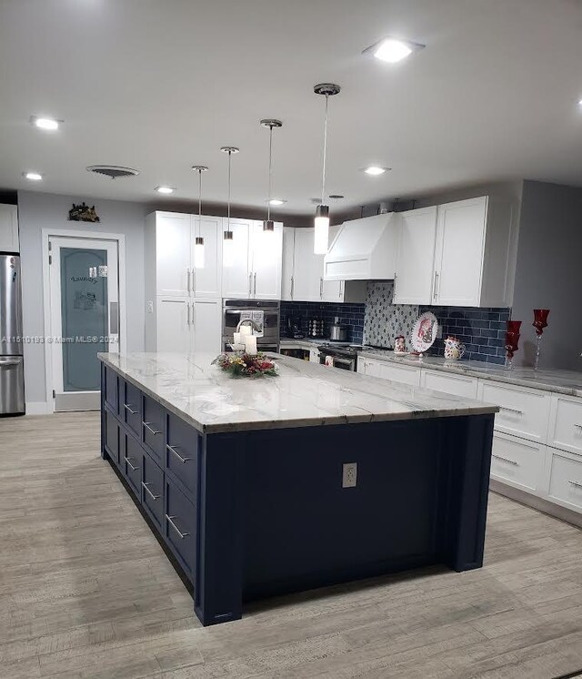 kitchen with stainless steel appliances, a center island, white cabinetry, custom range hood, and light wood-type flooring