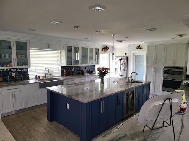 kitchen with pendant lighting, light stone countertops, appliances with stainless steel finishes, white cabinetry, and backsplash