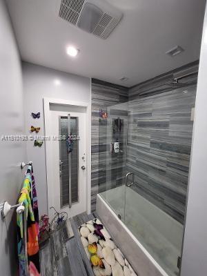 bathroom with bath / shower combo with glass door