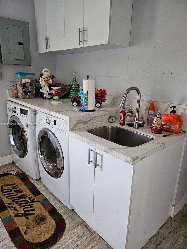 clothes washing area featuring cabinets, washing machine and clothes dryer, light wood-type flooring, and sink